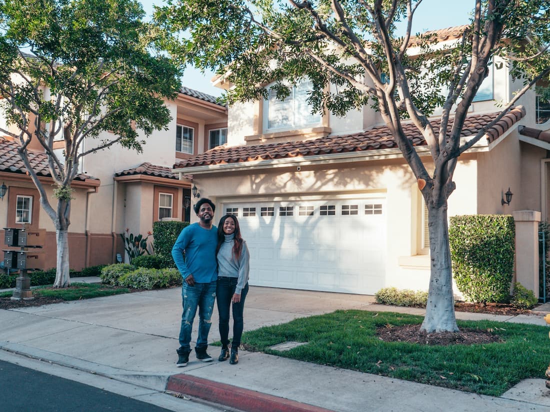 Happy couple standing in front of their new home